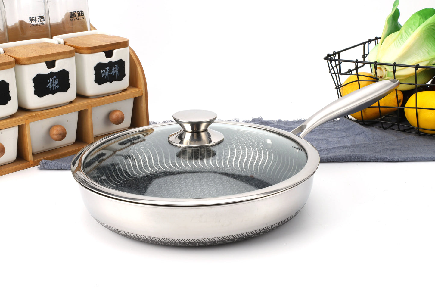 Stainless steel frying pan with glass lid on a kitchen counter