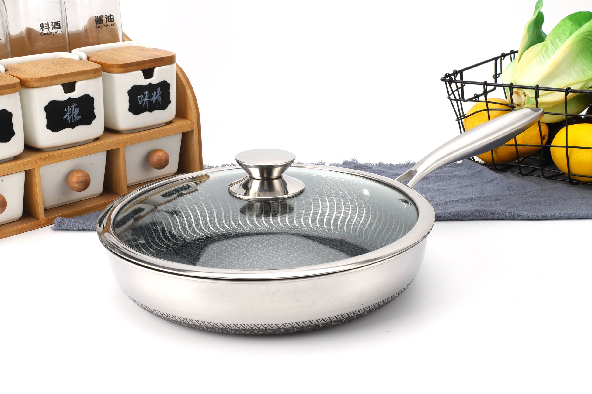 Stainless steel frying pan with glass lid on a kitchen counter