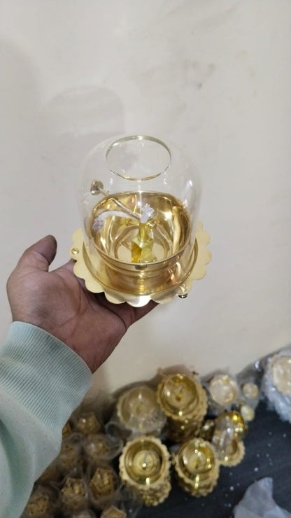 Hand holding a small glass container with a gold base on a light background