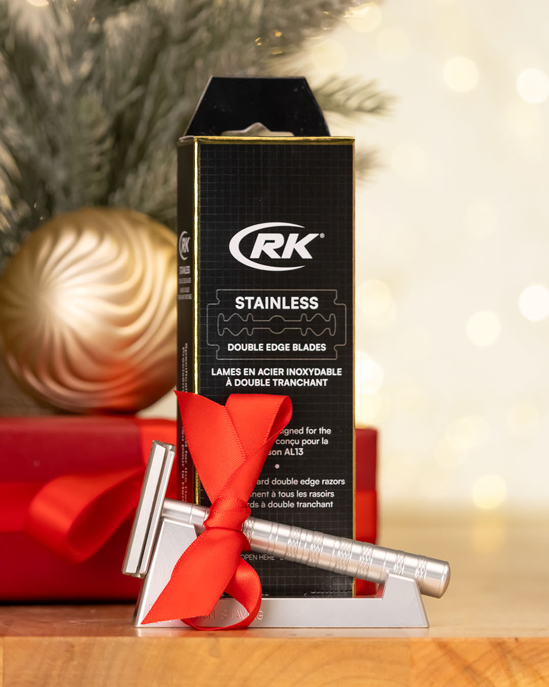 RK stainless double edge blades packaging with a silver razor and red ribbon on a blurred festive background